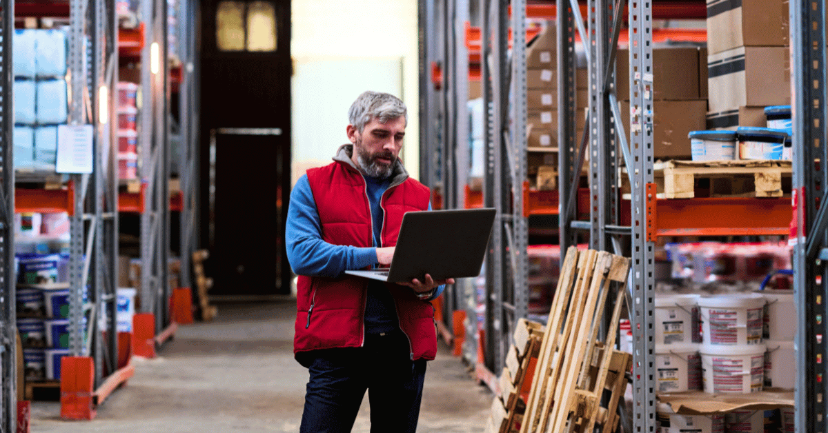 Man standing in warehouse operating a laptop - distributor loyalty
