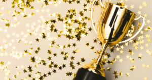 Gold trophy surrounded by gold stars, representing employee gamification