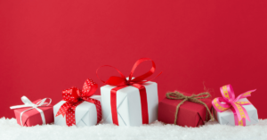 Red background with wrapped gift packages in the foreground featuring red and white colored - representing employee rewards ideas for the holidays