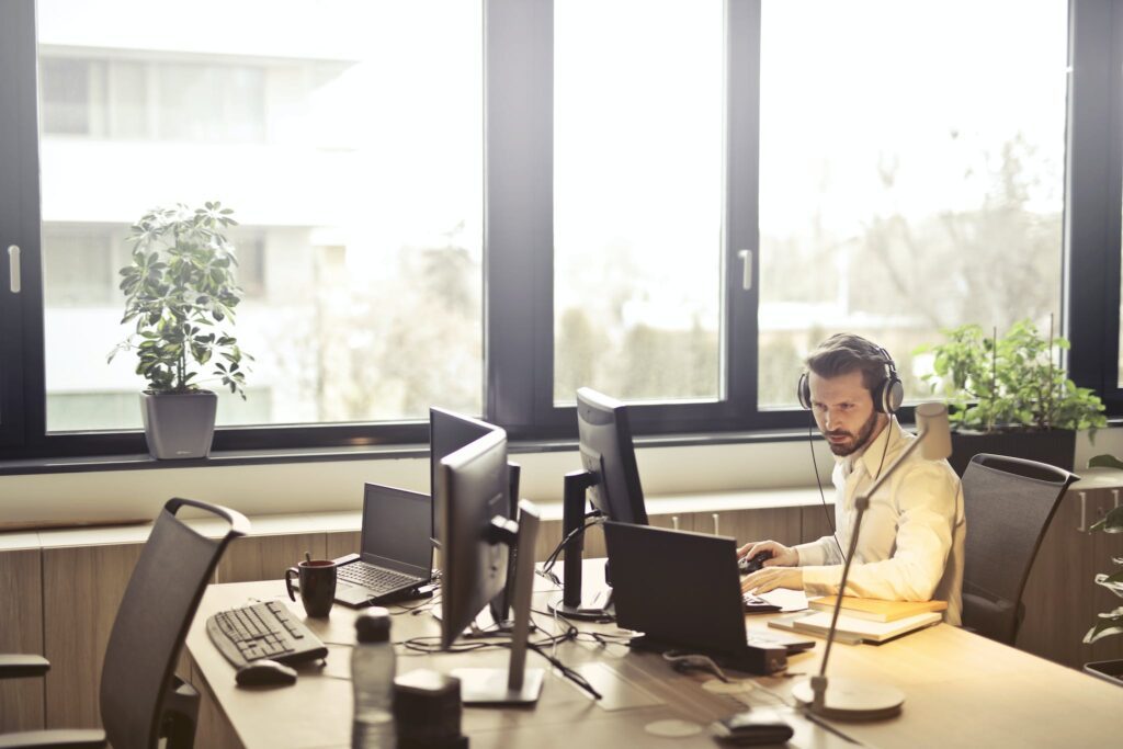 Man With Headphones Facing Computer Monitor - representing B2B loyalty program participant support services
