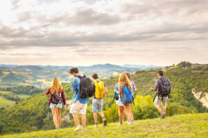 A group of people wearing backpacks, walking through green hills - incentive travel services