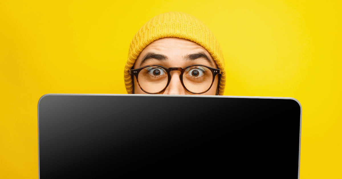 Person wearing yellow beanie peeking over laptop - Your Channel Isn’t Broken, Your B2B Rebates Are