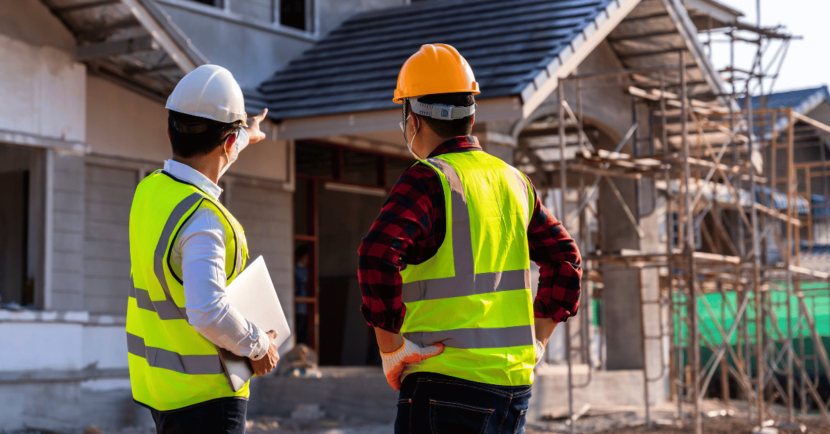 Builders facing away from camera, discussing house in background - How a Building Manufacturer Increased Sales 30%