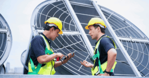Two HVAC techs talking in front of equipment - Help Contractors Retain HVAC Technicians