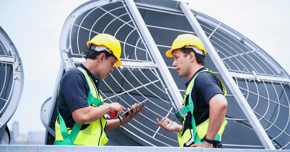 Two HVAC techs talking in front of equipment - Help Contractors Retain HVAC Technicians