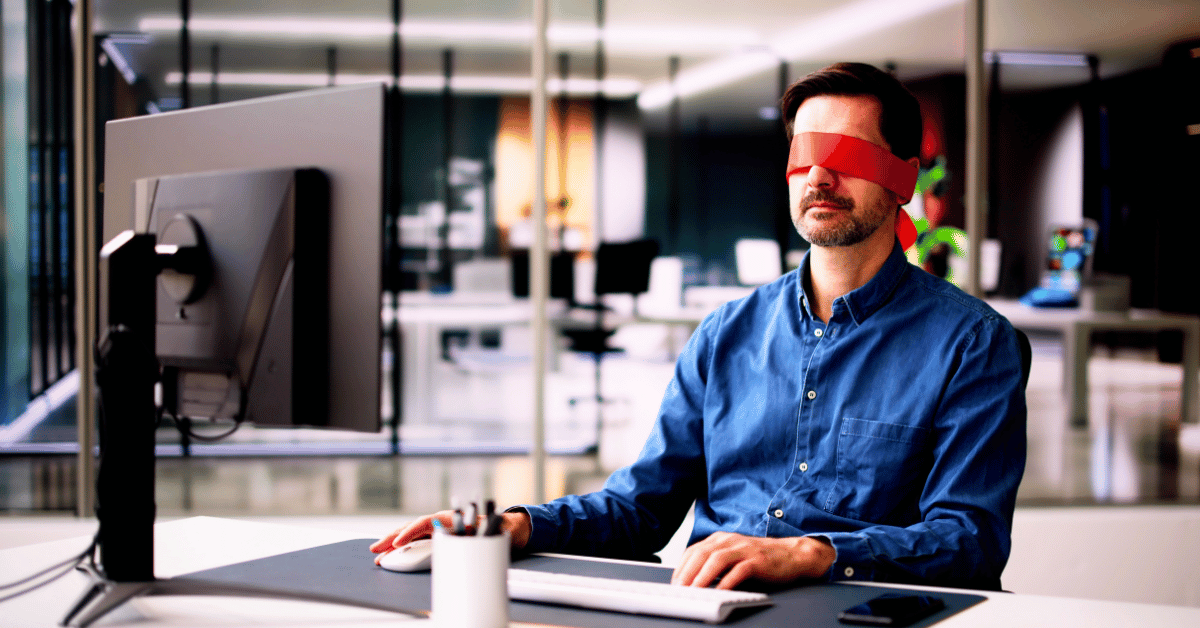 Man in office setting using computer blindfolded - The Open Secret in B2B Marketing is No One Knows What's Working or Why